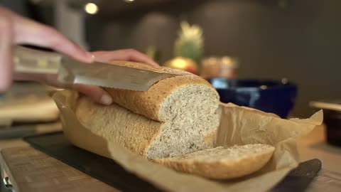 Close Up of Female Hands Slicing Loaf of Bread