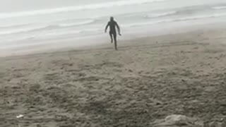 Guy in wetsuit on the beach does stretches