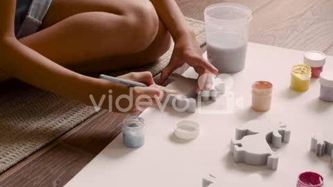 Close Up View Of Girl's Hands Painting Animal Pieces On The Floor