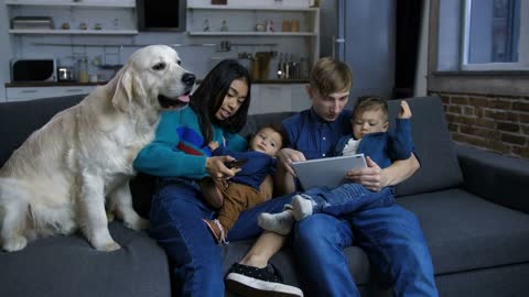 Multi ethnic family with little children and pet dog resting