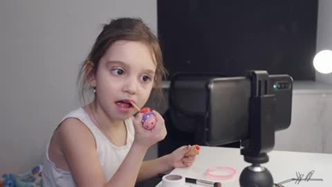 Little Girl Applying Lipstick While Looking At Her Smartphone & children world