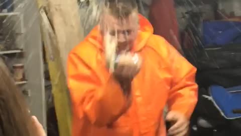 Music guy in orange jacket cracks beer over head and chugs in a garage