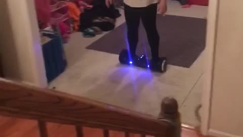 White shirt woman falls off hoverboard in front of stairs