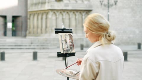 Back View of Female Artist Painting on Canvas in Street