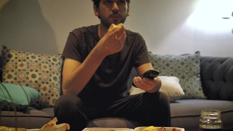 Man watching TV and eating fast food