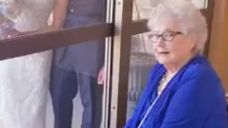 Bride visits her grandmother through glass on wedding day
