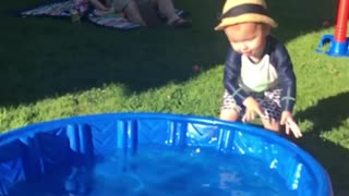 Little kid tries to walk blue kiddie pool but falls face first instead