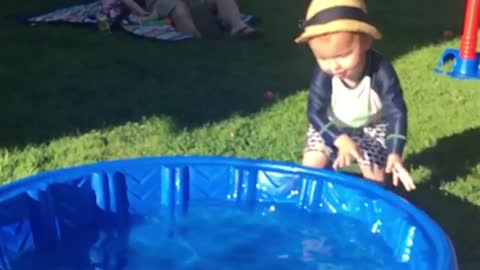 Little kid tries to walk blue kiddie pool but falls face first instead