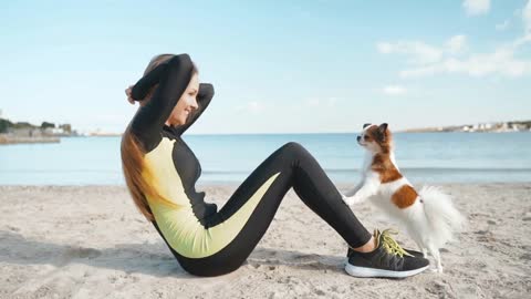 Young adult sporty woman training with little dog outdoor