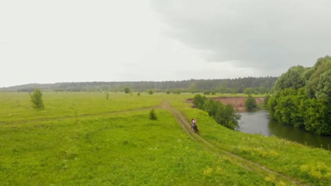 A landscape of a bright green field - a person riding a horse