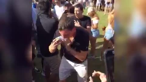 A guy in a black shirt is getting dumped in a bucket of ice, then chugs beer
