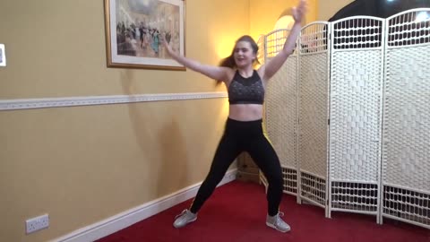 Aerobics in black leggings doing some arm and leg stretches