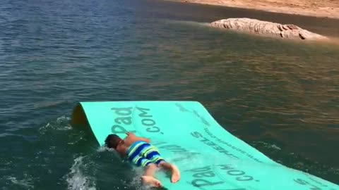 Boy slides down boat slide bellyflop on blue mat