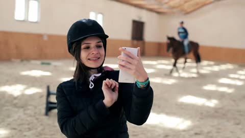 Young, woman with helmet taking selfie photo during horse riding lesson