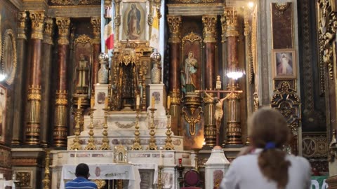 Lady praying in front of a large altar inside a church