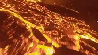 Drone flying over volcano and lava flow at night.