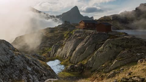 scenic summer shot of clouds passing by a mountain hut on the lofoten islands norway