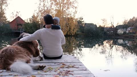 Friendship concept, a man with his son in his arms and a dog sitting together. Little boy hugs dad