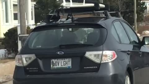 Black car drives off with white surfboard on roof