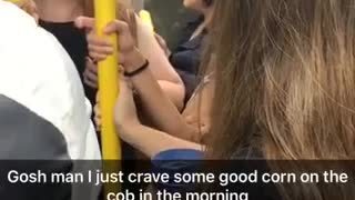 Girl in blue jacket eating corn on the cob on train