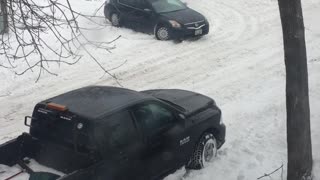 Stuck Car Struggles on Snowy Street