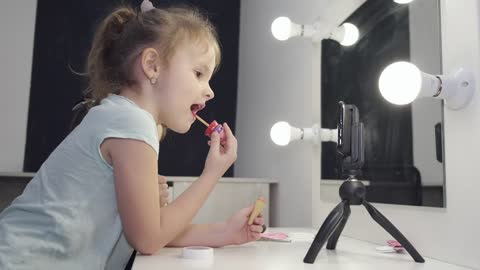 Two Little Girls Putting On Lipstick And Makeup