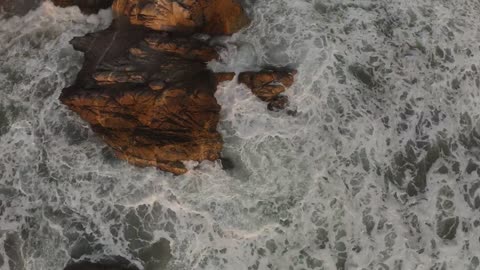 Waves crash on a shore with boulders