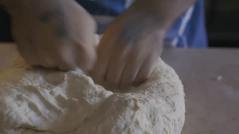 Hands of a baker kneading a dough
