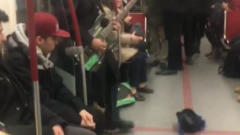 Two guys play electric guitar and violin on subway train