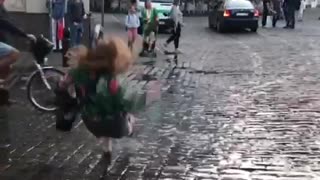 Woman in colorful jacket jumps in puddle and falls back