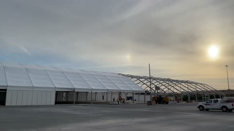 A huge tent in a grass field under sunny sky