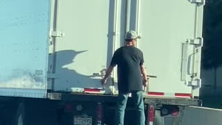 Man Hangs Onto Truck Traveling Along Highway