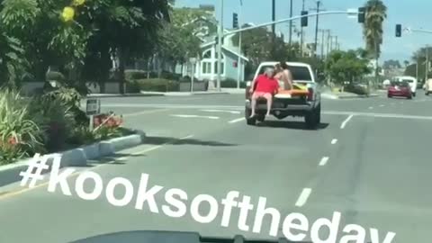 Red shirt guy riding on open trunk of truck