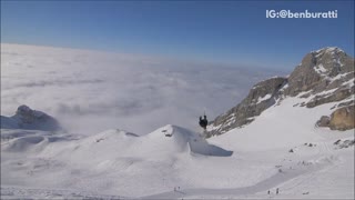 Guy in black backflips lands on back green skis