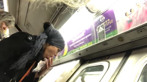 Woman on a subway train fingers her mouth