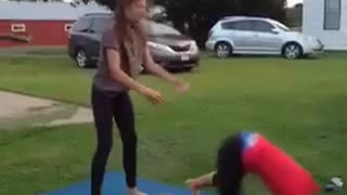 Two girls try to do a flip the one in red falls