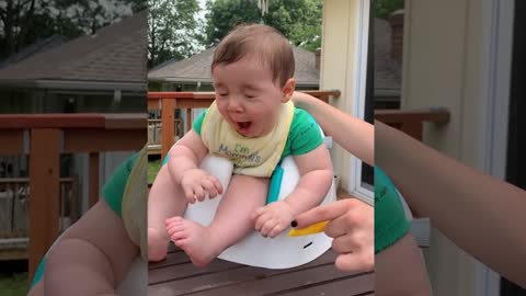 Funny baby sitting in a potty and tasting lemon