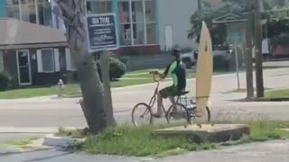 Guy riding bike with yellow board on back