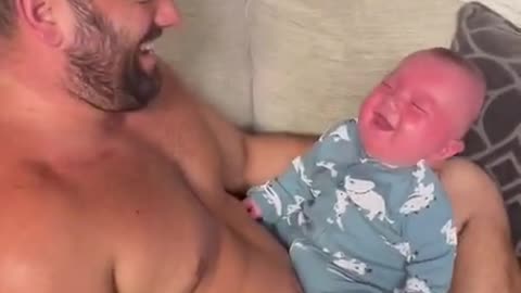 Funny baby is laughing laud while dad playing with a balloon