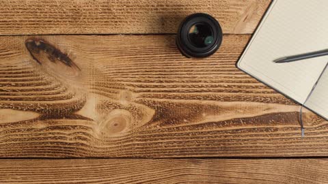 Top Down Shot of Person Picking Up an SLR Camera from Table with Left Copy Space