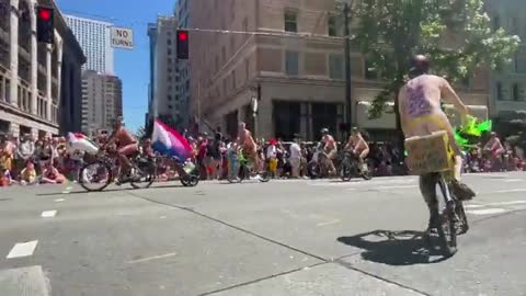 NAKED BICYCLISTS circling route in front of large crowd of children at Seattle Pride