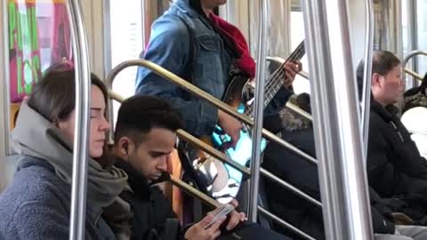 Man sings and plays bass guitar on subway train