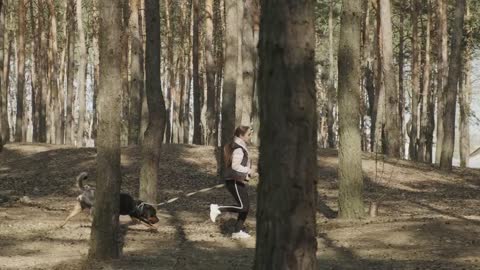 Woman running with her dog through the forest