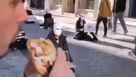 MAN EATING A BURGER A VEGAN PROTEST