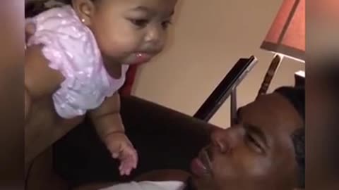 Cute baby girl loves blowing spit bubbles with Dad
