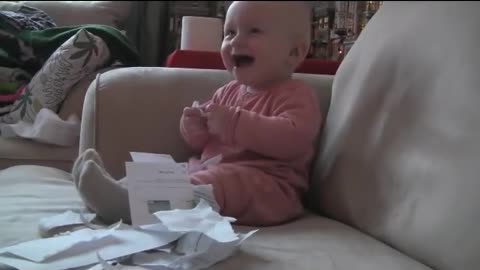 Cute baby laughing at ripping paper