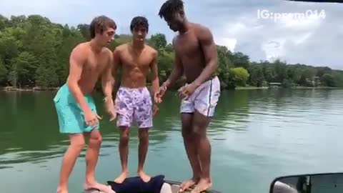 Three guys back flip off of boat guy on right fails hits boat