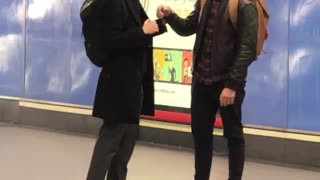 Two men play fight with their arms at subway station