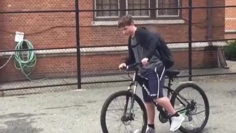 Shorts backpack kid does wheelie on bike and falls on back