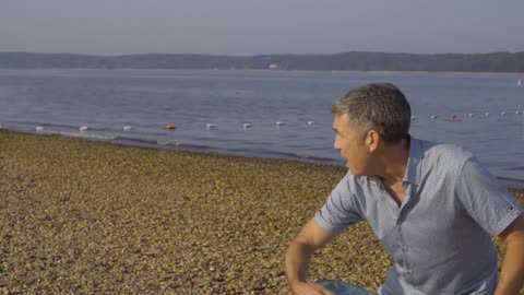 Man Plays Frisbee with Golden Retriever Dog on the Beach Shore in Long Island